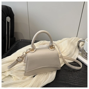 Detail of cream white leather handbag featuring litchi texture and gold hardware hooks