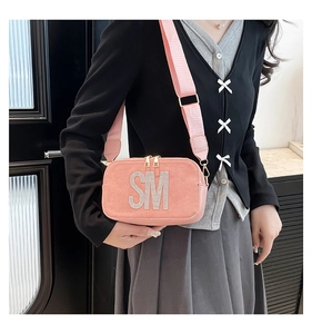 Pink crossbody camera bag featuring large rhinestone SM logo and wide fabric shoulder strap