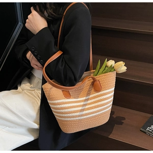 Détail d'un sac cabas tissé avec rayures blanches et anses en cuir marron en plein air