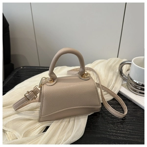 Detailed view of beige pebble leather mini handbag with gold-tone hardware and top handle