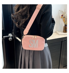 Detail of pink suede crossbody bag with sparkling rhinestone SM logo and wide strap