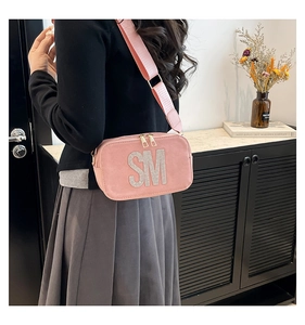 Detailed shot of pink suede crossbody bag with sparkling rhinestone SM lettering and wide strap
