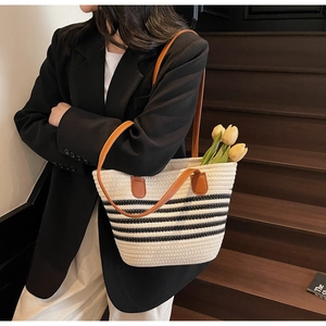 Détail du sac cabas tissé avec rayures noires et anses en cuir marron porté par mannequin
