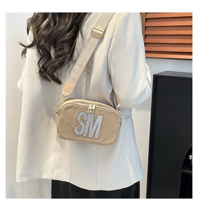 Macro shot of khaki crossbody bag with rhinestone SM initials and wide strap