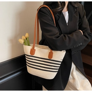 Détail du sac cabas tissé avec rayures noires et fines anses en cuir marron de qualité