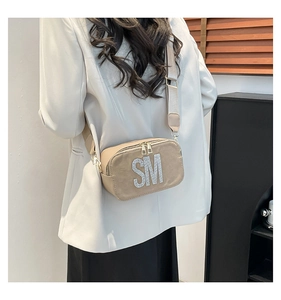 Detail view of beige crossbody camera bag with sparkling rhinestone SM letter design