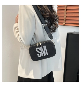 Black crossbody bag with rhinestone SM letters shown worn by a model in profile view