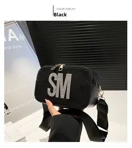 Detail of black matte crossbody bag with rhinestone SM logo and wide fabric strap