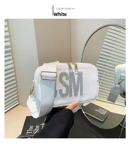 Detail of white square crossbody bag with rhinestone SM logo and wide nylon strap