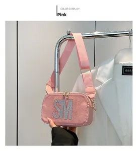 Detailed view of pink crossbody bag with rhinestone SM letter and wide strap