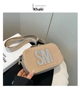Detail of khaki crossbody bag with rhinestone SM initials and wide fabric shoulder strap