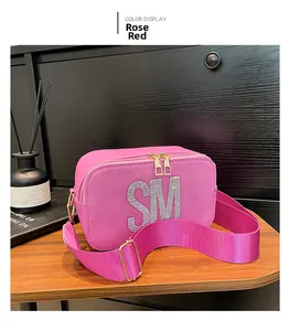 Detail of rose red crossbody bag with crystal SM letter and wide woven strap
