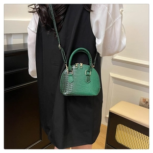 Borsa a conchiglia verde scuro con motivo a coccodrillo indossata dalla modella