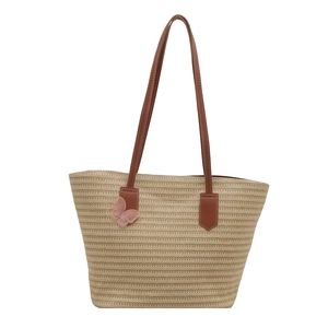 Woven straw tote bag with pink butterfly charm and slim brown shoulder straps