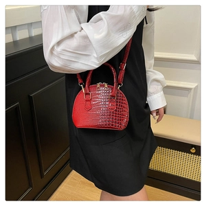 Dettaglio della mini borsa a conchiglia rossa in pelle coccodrillo con tracolla sottile