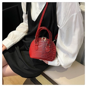Dettaglio borsa a conchiglia rosso scuro motivo coccodrillo con zip d'oro e manico
