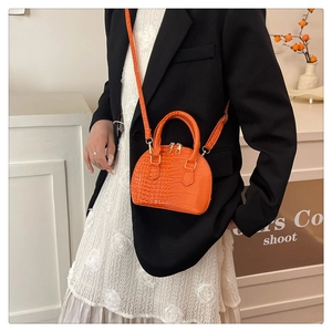 Modella con borsa a conchiglia arancione vivace effetto coccodrillo e dettagli dorati chic