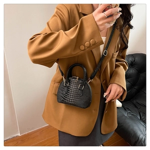 Borsa nera a conchiglia con trama coccodrillo indossata da modella con blazer