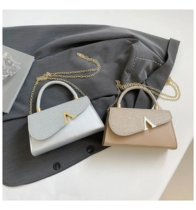 Detail of silver and beige evening bags with sparkling fabric and gold V-shaped buckles