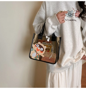 Dettaglio della borsa tote in PVC marrone trasparente con stampa cartoon e manici neri