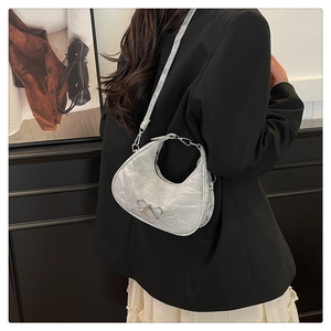 Detail of silver crescent bag with metallic crinkle texture and bow decoration