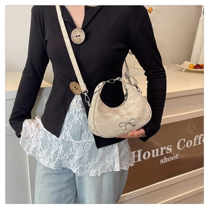 Detail of beige hobo bag featuring pleated texture and silver metal bow decoration