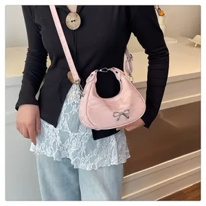 Pink crescent saddle bag with pleated texture and silver bow detail on model