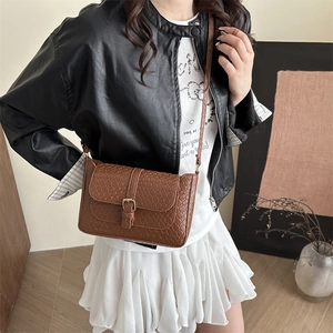 Brown woven texture crossbody bag with metal buckle shown on model in retro style