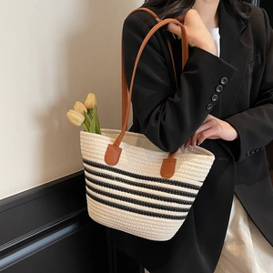 Sac fourre-tout tissé minimaliste à rayures noires avec des anses en cuir marron sur modèle