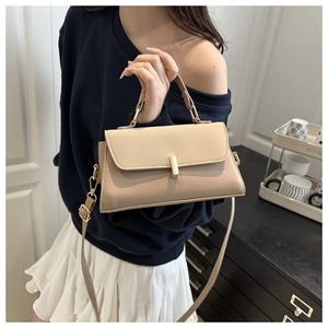 Detail of minimalist beige leather handbag with gold metal clasp and smooth texture