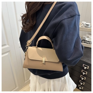 Detail view of beige leather bag with gold rectangular clasp and adjustable shoulder strap