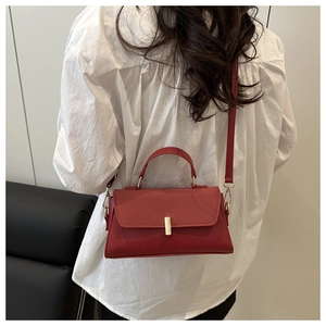 Detail of red leather crossbody bag featuring a sleek golden metal clasp and top handle