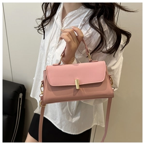Detailed view of a pink structured handbag featuring a sleek gold metal bar closure