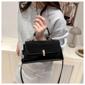Detail of a minimalist black handbag featuring matte texture and a sleek gold metal lock