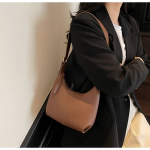 Brown matte leather hobo bag with vertical seam detail shown on model's shoulder