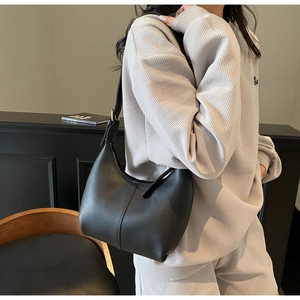 Detail view of black crescent shoulder bag with vertical stitching and adjustable gold buckle