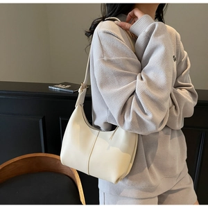 Close-up of creamy white half-moon shoulder bag with wide strap and matte leather texture