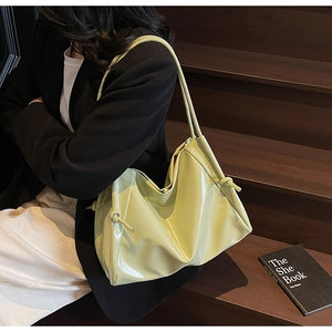 Detail of light green glossy shoulder bag with knot detail and polished texture
