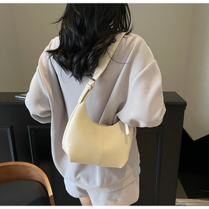 Detail of minimalist beige faux leather hobo bag with vertical stitching and adjustable strap