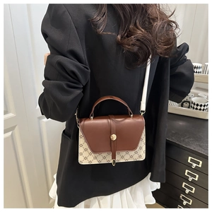 Detail of a vintage-style jacquard canvas handbag with leather trim shown on model