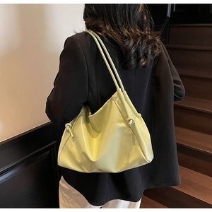Detail of light green patent leather tote bag with side drawstring knot decoration