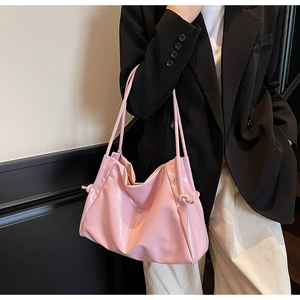 Detail of pink glossy tote bag featuring unique knot design and pleated leather texture
