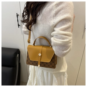 Close-up of retro color-block handbag with monogram pattern and gold metal buckle