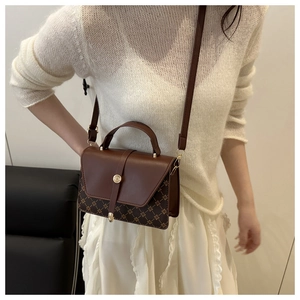 Detail view of vintage dark brown crossbody bag with floral pattern and metal buckle