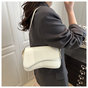 Detail of cream shoulder bag featuring asymmetrical flap design and smooth PU leather finish