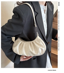 Détail du sac nuage plissé beige avec boucles argentées sur une épaule en noir