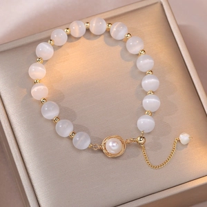 Cat eye stone and freshwater pearl bracelet with golden metallic accents and adjustable chain