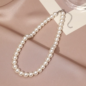 Elegant single-layer pearl necklace with silver lobster clasp on champagne satin background