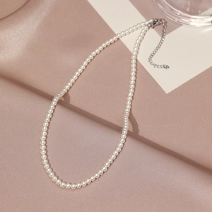 Detailed view of elegant pearl necklace with silver lobster clasp on silk fabric