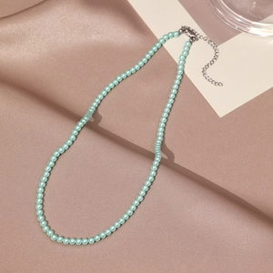 Détail du collier de perles vert menthe avec fermoir mousqueton argenté sur du satin